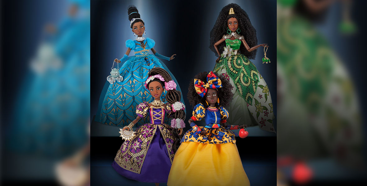 A photo of the four dolls from the CreativeSoul Photography collaboration, each inspired by a classic Disney Princess. The dolls are Black with natural hair and ornate, Afrocentric dresses. The Cinderella-inspired doll wears a brilliant blue gown and carries a carriage purse, while the Tiana-inspired doll’s dress has gold embellishments. The Rapunzel-inspired doll wears long locs clasped by flowers and a puffed-sleeve purple dress, and the Snow White-inspired doll wears an afro with a blue, red, and yellow bow and a gown in the same colors.