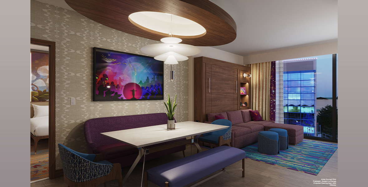 Concept art for one of the one-and-two bedroom villas at The Villas at Disneyland Hotel. A dining table surrounded by blue and purple seating is seen in the foreground; a large white lighting fixture is above the table, and Disney art hangs on the wall. Towards the right, a purple couch and some ottomans are seen near a window. To the left, a small portion of a doorway into a bedroom is seen.