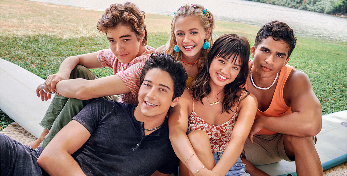 In a promotional photo for Doogie Kamealoha, M.D., Matthew Sato, Milo Manheim, Emma Meisel, Peyton Elizabeth Lee, and Alex Aiono pose on surf boards and palm leaves. They are all wearing beachy outfits and are smiling for the camera.