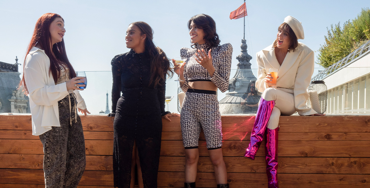 In a scene from an episode of Love Trip: Paris, Caroline Renner, Josielyn Aguilera, Lacy Hartselle, and Rose Zilla-Ba stand on a rooftop in Paris during daytime and talk.