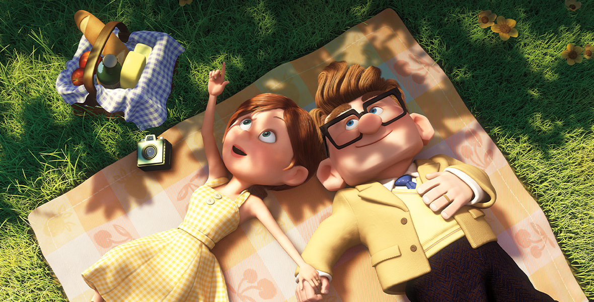 In the animated film Up, Carl and Ellie lie on their backs on a picnic blanket in the grass. Ellie wears a yellow picnic dress and points at a cloud in the sky as she holds Carl’s hand. Carl looks up, matching Ellie in a yellow suit and blue tie. An old camera lies on the blanket, and a basket of bread, two apples, a cheese wheel, and a bottle are assembled on the grass.