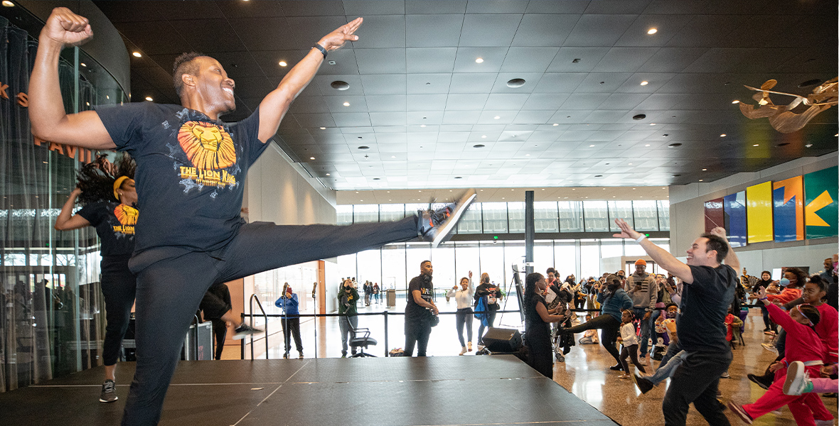 In one of the museum’s wide halls, two performers sporting The Lion King T-shirts kick their left feet in the air. A crowd of people tries to mimic them as they learn the choreography.