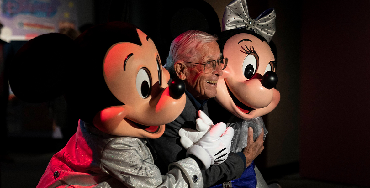 Mickey and Minnie hug Disney Legend Bob Gurr.