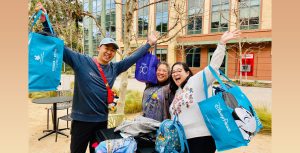 Excited D23 Gold Members beam as they hold their arms full of shopping bags up in the air.