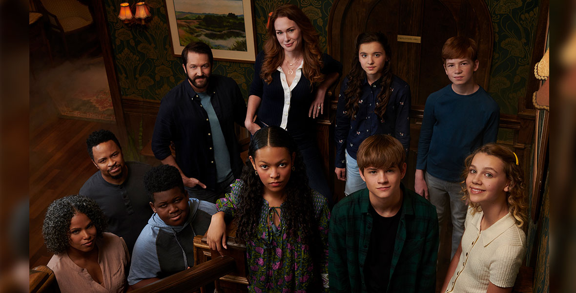 The cast of Secrets of Sulphur Springs stands on a wooden staircase on the show’s set.
