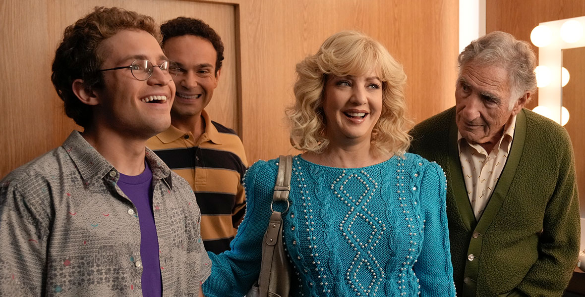 Four cast members from ABC’s The Goldbergs stand together in what appears to be a dressing room. They are, from left to right, Sean Giambrone, Troy Gentile, Wendy McLendon-Covey, and Judd Hirsch.