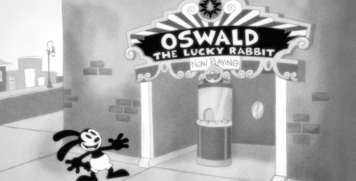 The black and white animated character Oswald the Lucky Rabbit stands outside a brick movie theater with a big smile on his face. His arms are outstretched and his rabbit ears leaning backward. An art deco marquee says, “Oswald the Lucky Rabbit Now Playing.” There is a ticket window and two doors just below the marquee.