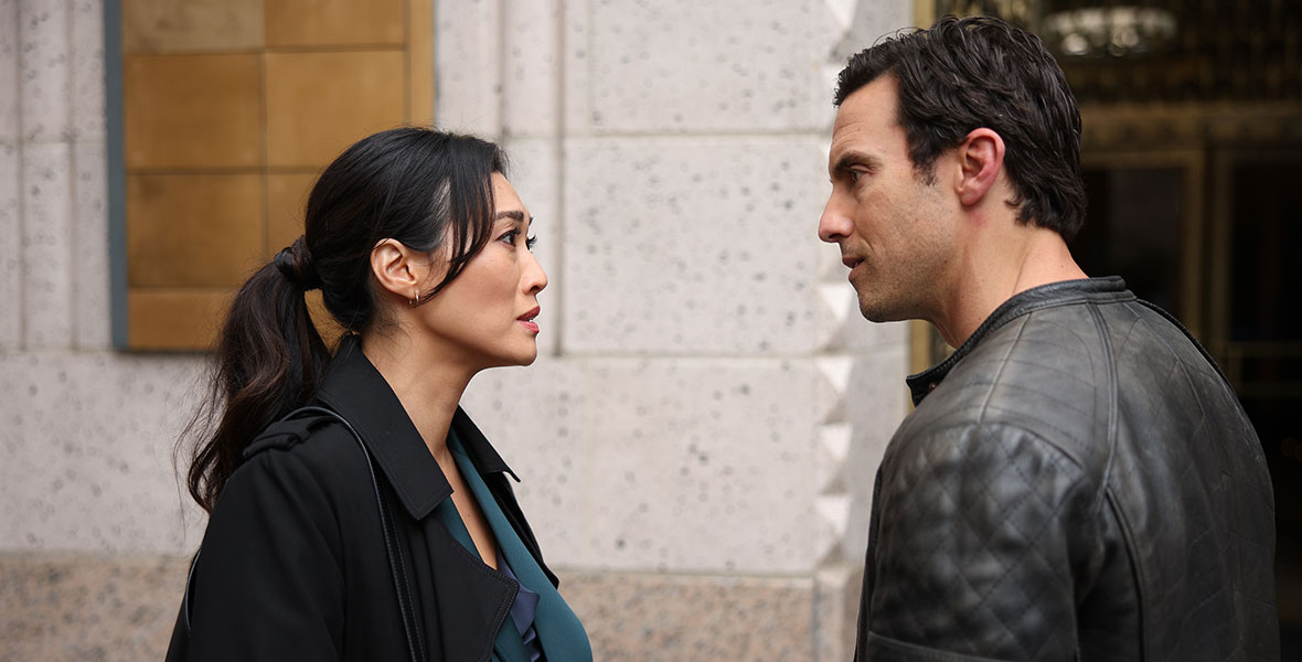 In a scene from an episode of The Company You Keep, actors Catherine Haena Kim and Milo Ventimiglia talk outside of a stark, stone building.