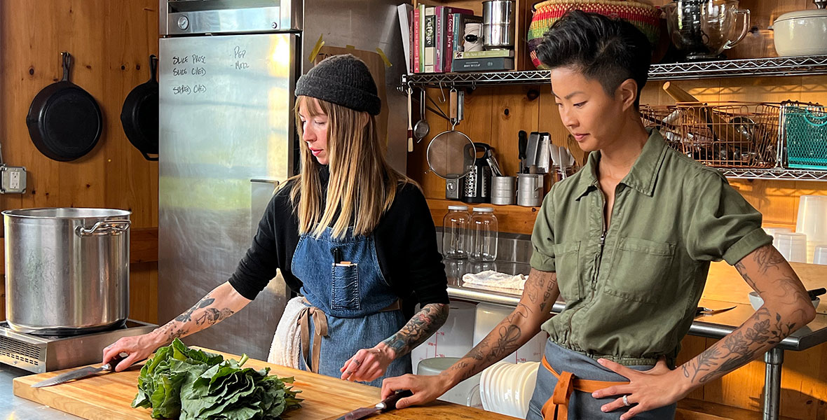 Chefs Carolynn Ladd and Kristen Kish cook together in a kitchen.