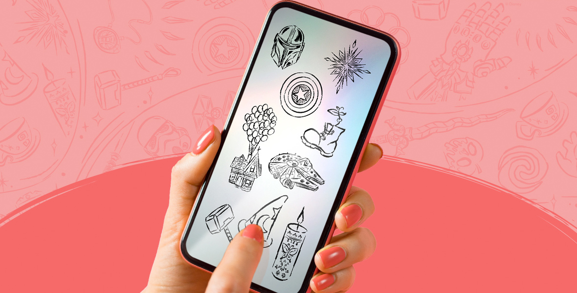 A hand holding a phone against a salmon and pink background. The phone screen is illuminated to show a page full of Disney sketches. From top left to right are a Mandalorian helmet, Captain America’s shield, a snowflake from Frozen, the boot from WALL-E, the floating house from UP, the Millennium Falcon, Thor’s hammer (Mjolnir), Mickey’s sorcerer hat, and the candle from Encanto. Light sketches of the same icons are printed across the pink background behind the phone.