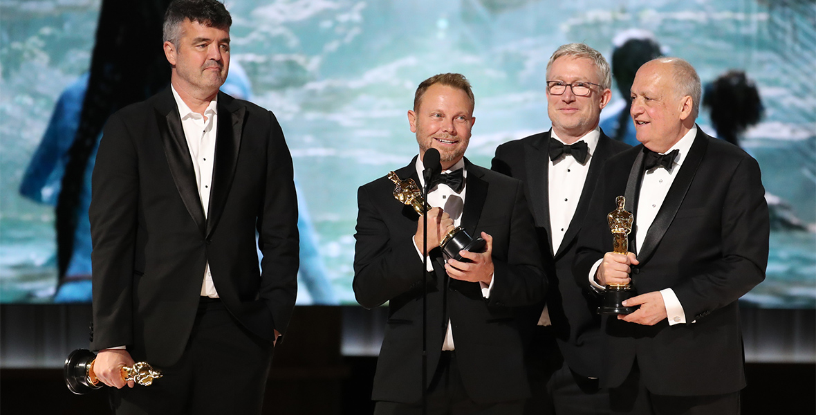 From left to right, Avatar: The Way of Water’s Eric Saindon, Richard Baneham, Daniel Barrett, and Joe Letteri stand onstage to accept their Best Visual Effects Oscars.