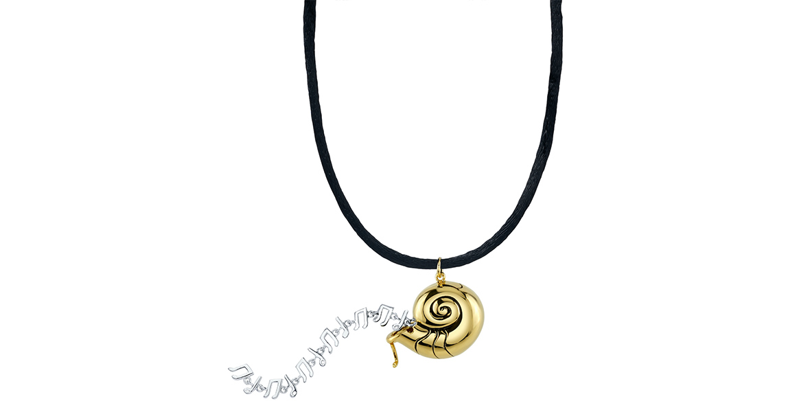 A close up of a necklace with a gold locket shaped like the nautilus shell that Ursula wore in The Little Mermaid. Coming out of the shell are silver music notes, representing Ariel’s “voice.”