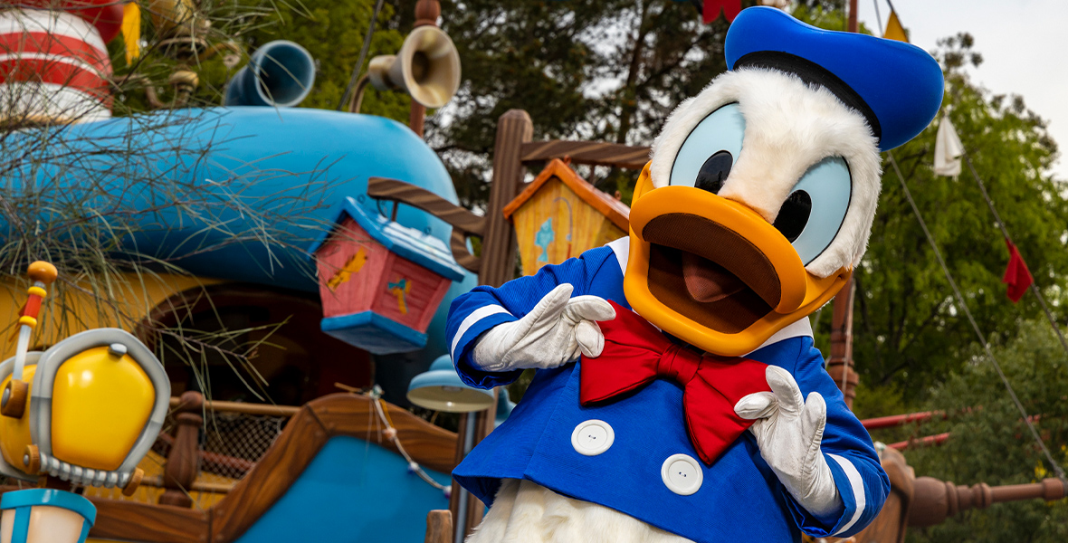 Donald Duck adjusts his red bow tie outside his boat in Mickey’s Toontown. Donald’s boat is massive and vibrant with quirky birdhouses, mailboxes, and clotheslines.