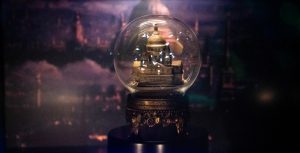 A snow globe depicting a miniature version of St. Paul’s Cathedral sits in front of a screencap of the “Feed the Birds” scene from Mary Poppins. The images of white, flying birds are projected as to appear inside the snow globe.