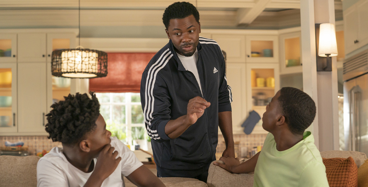 In a scene from an episode of The Crossover, actor Derek Luke leans over a couch to speak to actors Jalyn Hall and Amir O’Neil.