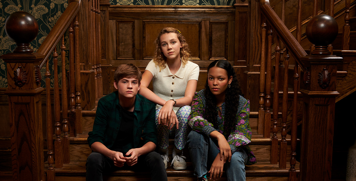 In a publicity still for Secrets of Sulphur Springs, actors Preston Oliver, Kyliegh Curran, and Elle Graham sit on a staircase.