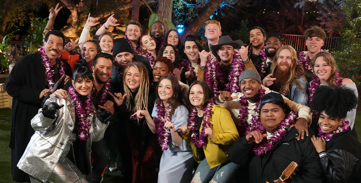 American Idol judges Lionel Richie, Luke Bryan, and Katy Perry pose with the Season 21 contestants, as everyone wears purple and white leis around their necks.