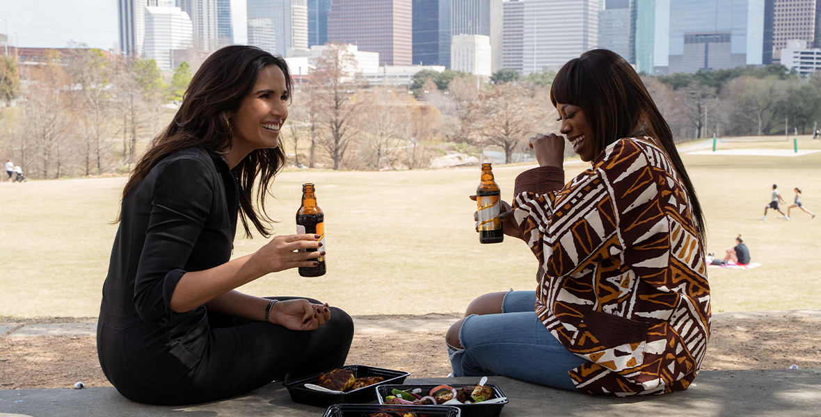 In a scene from Taste the Nation with Padma Lakshmi, host Padma Lakshmi eats Nigerian food with actor Yvonne Orji.