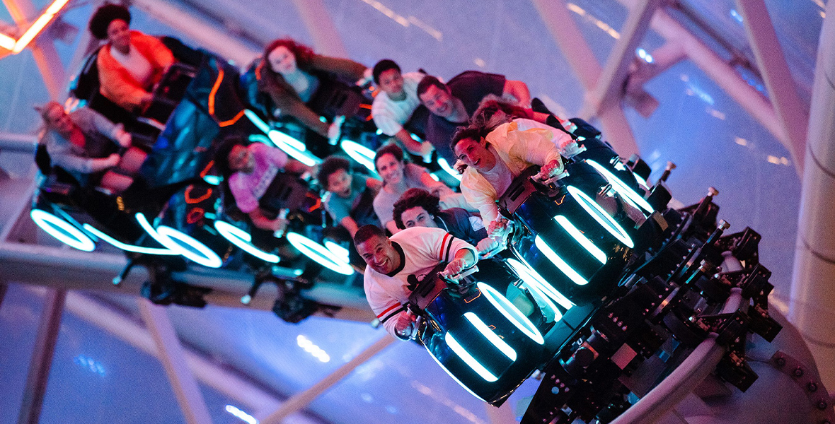 Guests aboard their Lightcycle train smile excitedly as they experience racing on the Grid.