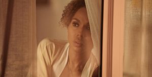 UnPrisoned, Kerry Washington peers through a window curtain.