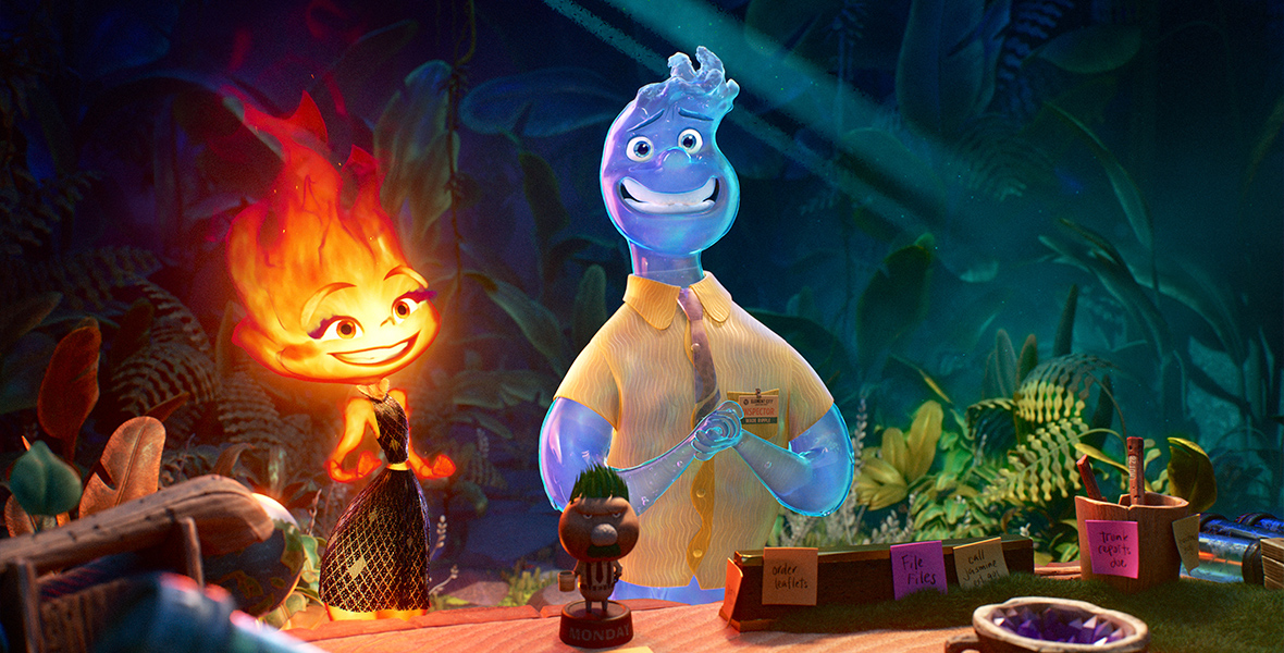 In a scene from the Pixar Animation Studios feature Elemental, Ember, a female fire person, and Wade, a male water person, stand in front of a desk that has common office objects on it. The person behind the desk is out of frame. Ember and Wade are both smiling, and behind them is an assortment of plants.