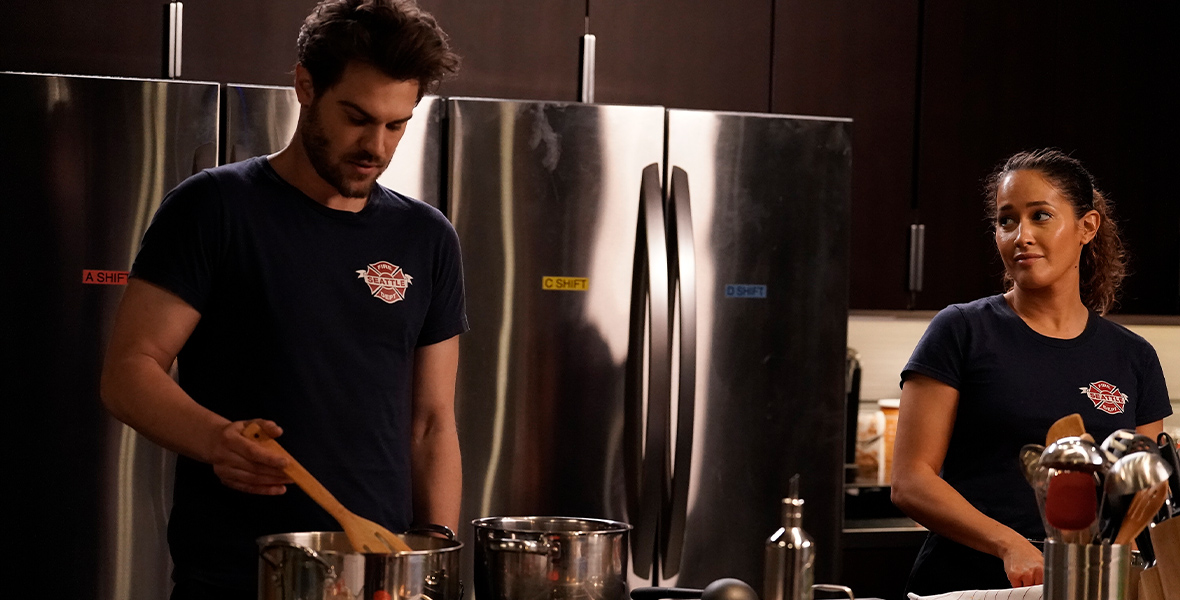 In a scene from Station 19, actors Grey Damon and Jaina Lee Ortiz cook in the station’s kitchen.