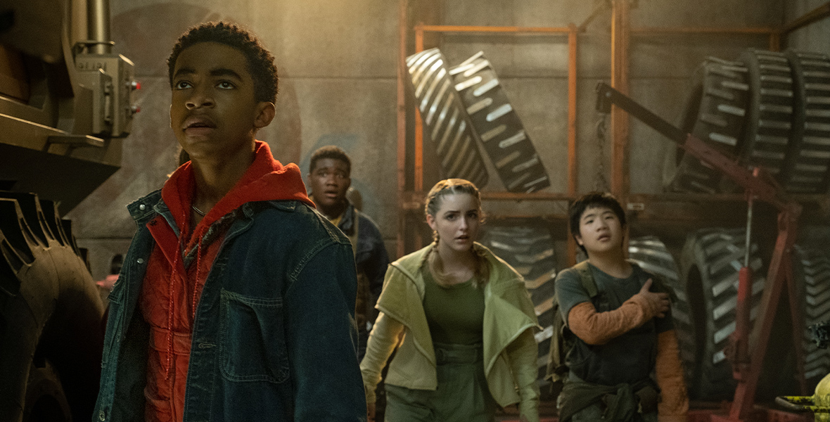 In a still from Crater, Caleb (Isaiah Russell-Bailey), Marcus (Thomas Boyce), Addison (Mckenna Grace), and Borney (Orson Hong) appear afraid as they walk through an industrial area.