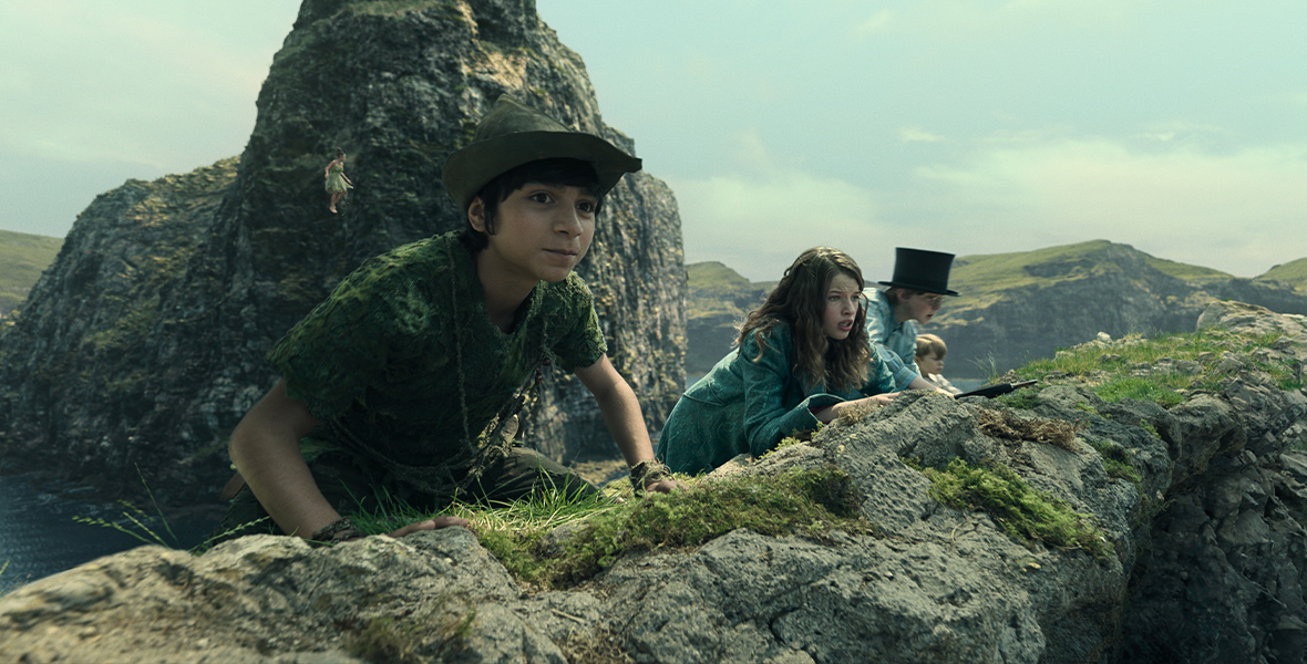 Left to right: Peter Pan (Alexander Molony), Wendy Darling (Ever Anderson), John Darling (Joshua Pickering), and Michael Darling (Jacobi Jupe) peer over a cliff’s edge.