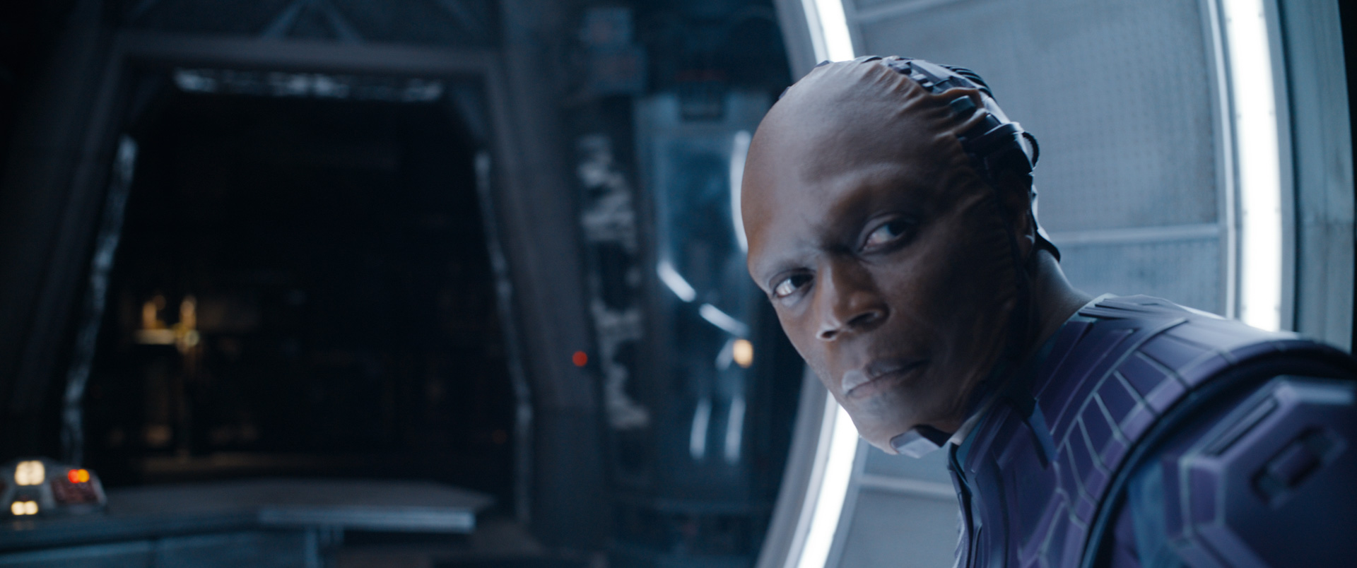 An image of Chukwudi Iwuji as The High Evolutionary in Guardians of the Galaxy Vol. 3. He stares over his shoulder, and while his face appears as a human, the back half of his head is seemingly made of metal.