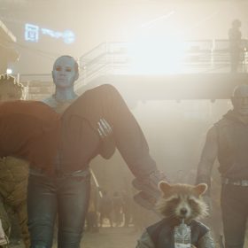 In a scene from Marvel Studios’ Guardians of the Galaxy Vol. 3, from left to right, Kraglin (Sean Gunn), Groot (voiced by Vin Diesel), Nebula (Karen Gillan) holding Peter (Chris Pratt), Rocket (voiced by Bradley Cooper), Drax (Dave Bautista), and Mantis (Pom Klementieff) are walking intently toward the camera.
