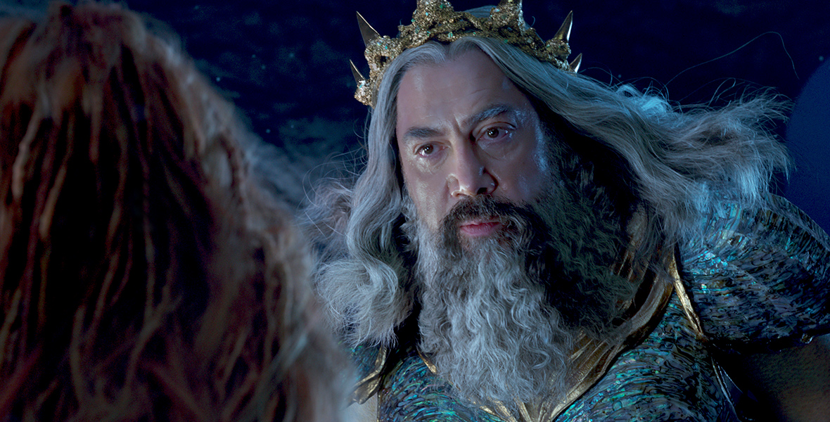 King Triton (Javier Bardem) addresses his daughter Ariel, whose back is toward the camera, in his underwater kingdom in a scene from the live-action The Little Mermaid.