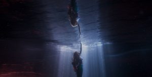 Ariel (Halle Bailey) swims up to the ocean’s surface, fascinated by the shadow of a large ship and the world beyond her underwater kingdom.