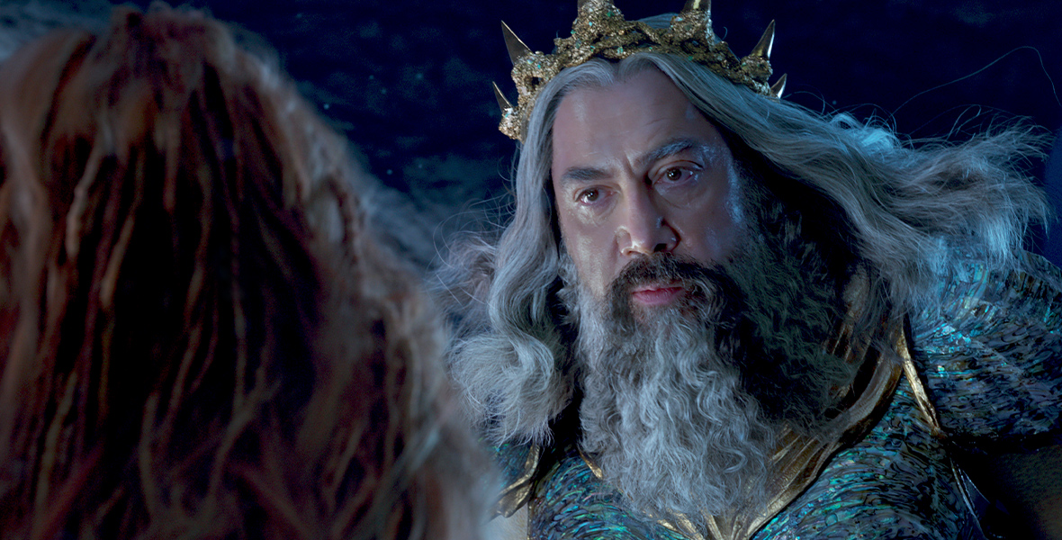 King Triton (Javier Bardem) addresses his daughter Ariel, whose back is toward the camera, in his underwater kingdom in a scene from the live-action The Little Mermaid.