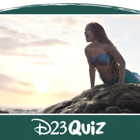 In a scene from The Little Mermaid, the mermaid Ariel (Halle Bailey) perches on a rock above the ocean’s surface. She sings out as the sun rises behind her, and the cloudy sky is a pale yellow. Her tail is an iridescent green, long and intricate.