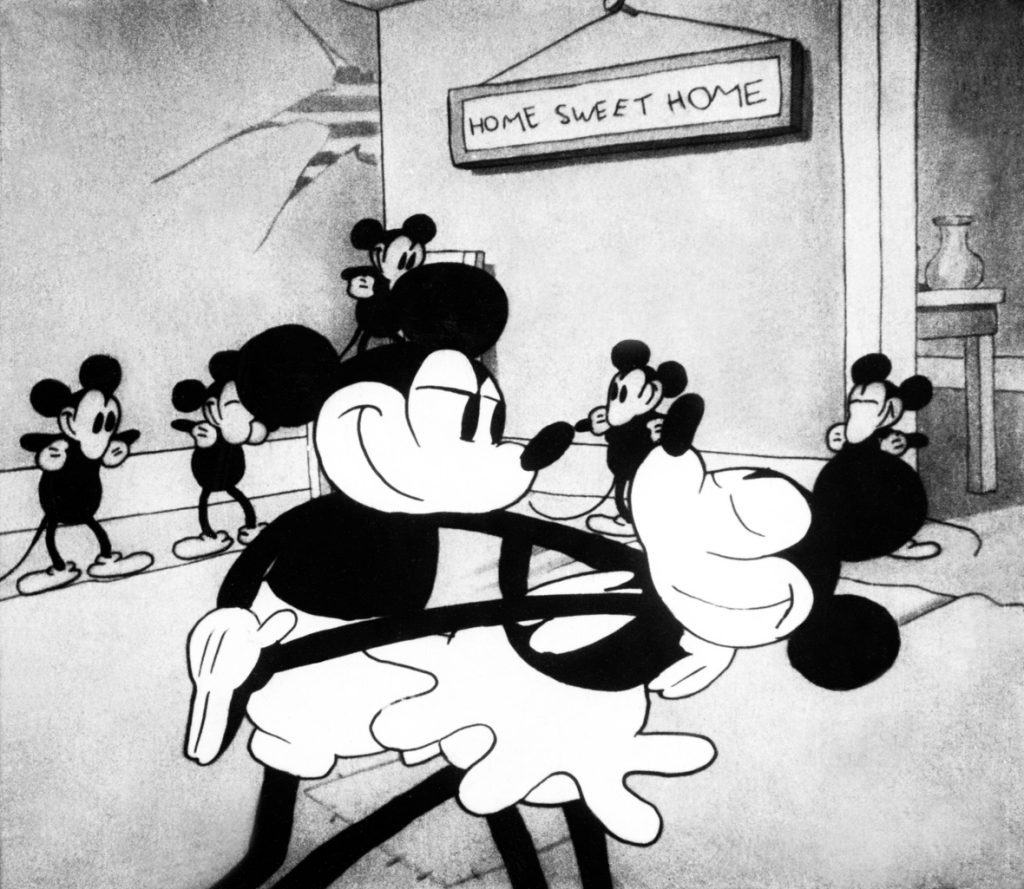 In this image from the animated short When the Cat’s Away, Mickey Mouse and Minnie Mouse dance in the middle of a room, while other mice stand in the background. Mickey, on the left, is dipping Minnie. There’s a sign hanging on the wall behind them that reads Home Sweet Home.