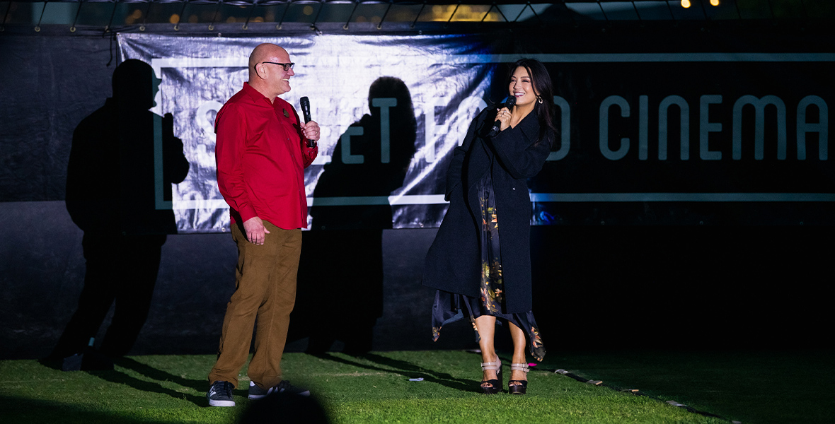 Michael Vargo and Ming-Na Wen share a heartwarming talkback on microphones in front of the projection screen at the outdoor screening event in the LA State Historic Park.