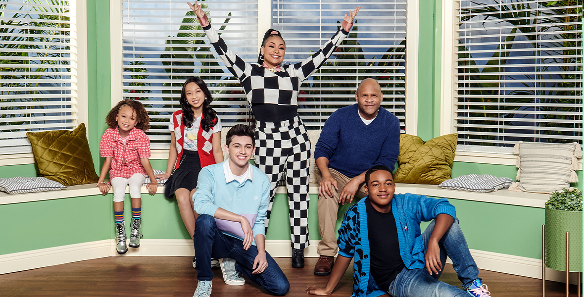 The cast of Disney Channel’s Raven’s Home, in a promotional image from the series. From left to right are Mykal-Michelle Harris as Alice, Emmy Liu-Wang as Ivy, Felix Avitia as Neil, Raven-Symoné as Raven Baxter, Rondell Sheridan as Victor Baxter, and Issac Ryan Brown as Booker Baxter-Carter. They’re seated or (in Raven’s case) standing in front of a picture window in a living room, and they’re all smiling at the camera.