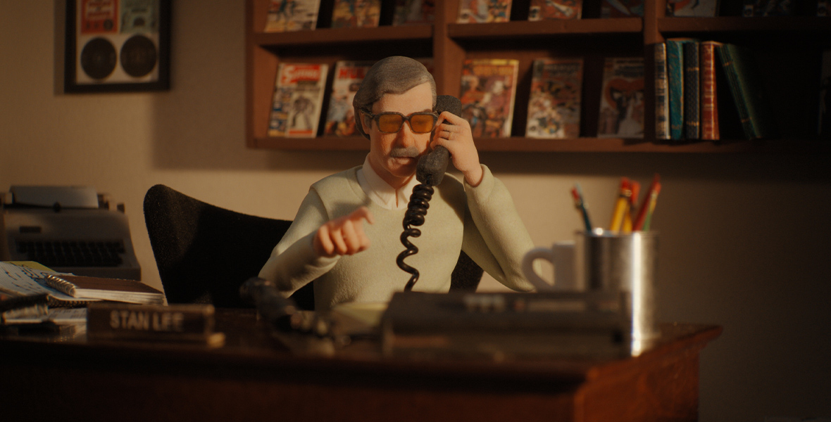 A miniature of Stan Lee makes a phone call from his desk.