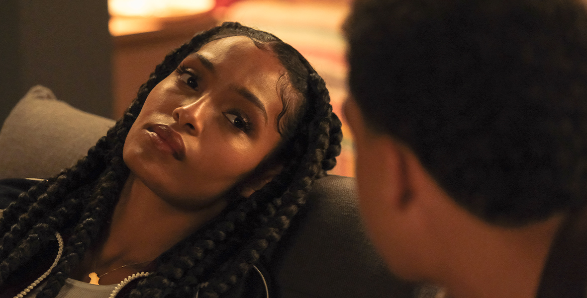 Zoey Johnson (Yara Shahidi) reclines on a gray couch and looks at her younger brother, Andre “Junior” Johnson (Marcus Scribner), in a scene from Season 5 of grown-ish.
