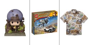 A Funko Pop! Vinyl figure depicting the opening sequence of Indiana Jones and the Raiders of the Lost Ark where Indy runs away from a boulder. A LEGO set depicts Indy and Marian trapped inside a lost tomb with snakes and Anubis statues, recreating a scene from Indiana Jones and the Raiders of the Lost Ark. A tan, button-down shirt with hand-illustrated art depicting classic scenes from the film Indiana Jones and the Raiders of the Lost Ark, including imagery of Indiana Jones using his whip and running from a boulder.