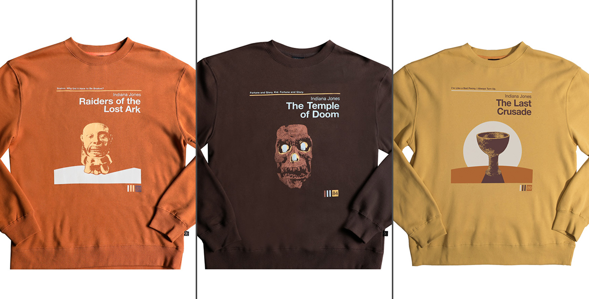 Three crewneck sweatshirts depicting vintage poster-style artwork for three Indiana Jones films. The first shirt is burnt orange, featuring the idol from Indiana Jones and the Raiders of the Lost Ark along with the film’s title in white text. The next shirt is dark brown and features a skull from Indiana Jones and the Temple of Doom, along with the film title in white text. The final shirt is golden yellow, with the Holy Grail from Indiana Jones and the Last Crusade, along with the film title in brown text.