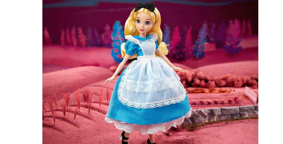 An articulated doll designed to look like the animated Alice from Disney’s Alice In Wonderland. She stands in a pink-hued set designed to resemble wonderland.