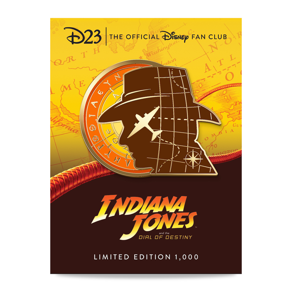 The D23 Member exclusive pin honoring the film Indiana Jones and the Dial of Destiny is depicted. The pin consists of silhouette of the head and hat of Indiana Jones, with an airplane superimposed on it. Behind Indy’s head is an orange and yellow circle representing the sun.