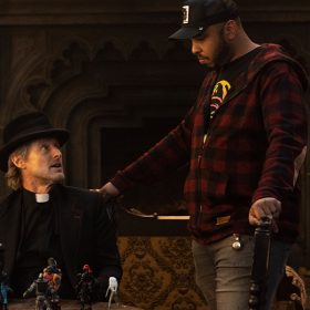 Actor Owen Wilson (left) is seated as he prepares to film a scene for Walt Disney Pictures' Haunted Mansion. Justin Simien (right) stands above Wilson, giving him direction.