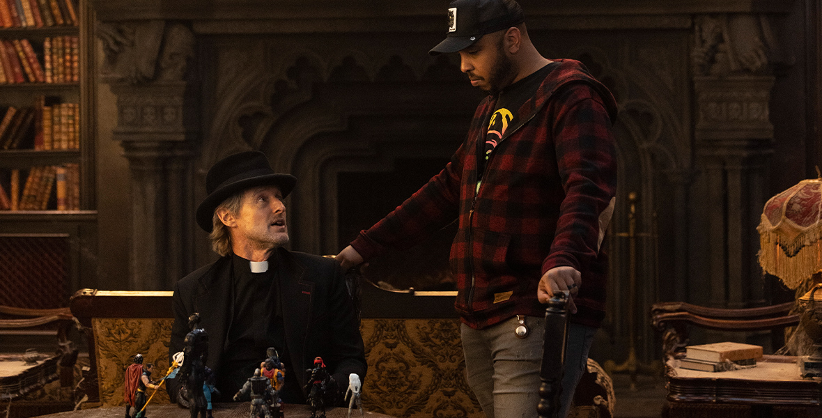 Actor Owen Wilson (left) is seated as he prepares to film a scene for Walt Disney Pictures' Haunted Mansion. Justin Simien (right) stands above Wilson, giving him direction.