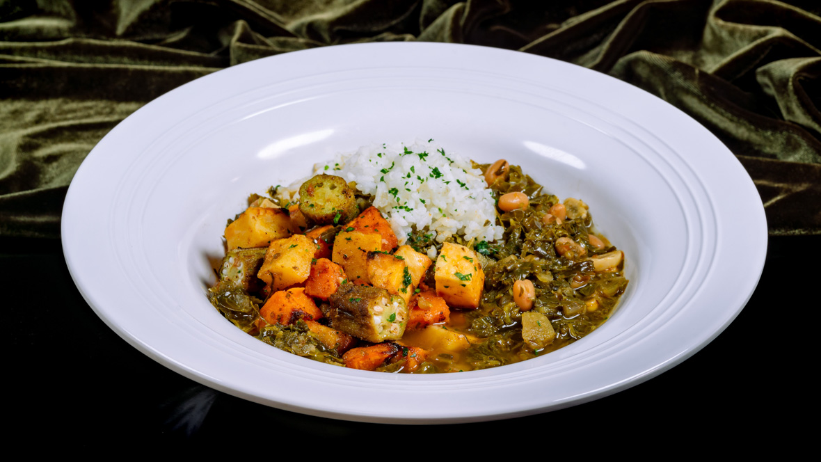 A bowl contains a serving of the plant-based 7 Greens Gumbo and white rice, as served at Tiana’s Palace.