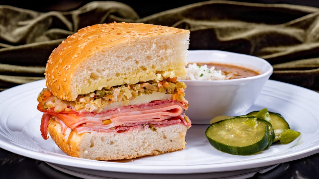 Muffuletta Sandwich (Tiana’s Palace at Disneyland Park in Anaheim, Calif.) – mortadella, salami, rosemary ham, cheddar, provolone and house-made olive relish on toasted New Orleans sesame seed bread, served with red beans &amp; rice and house-made pickles. Available beginning Sept. 7, 2023. For more details, visit DisneyParksBlog.com. (David Nguyen/Disneyland Resort)