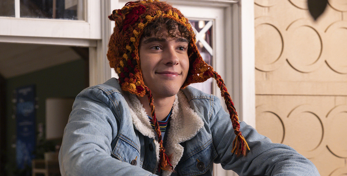 Actor Joshua Bassett, wearing a knit hat and a jean jacket, sits on set in a scene from the High School Musical: The Musical: The Series Season 4 episode "Night of Nights."