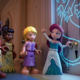 The LEGO versions of Snow White, Moana, Tiana, Rapunzel, and Ariel stand in front of a door with a glowing dragon inscribed on it