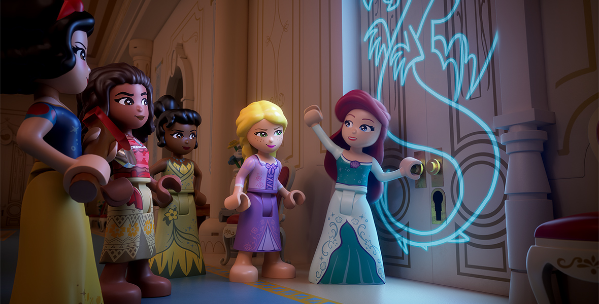 The LEGO versions of Snow White, Moana, Tiana, Rapunzel, and Ariel stand in front of a door with a glowing dragon inscribed on it